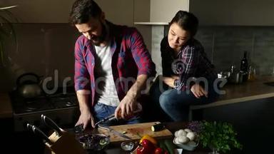 漂亮的年轻夫妇在家厨房做饭时吃健康的食物。 人浇沙拉油和盐。 女人吻男人。 <strong>情景</strong>
